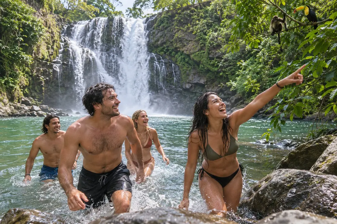 Travelers splashing beneath a Costa Rican waterfall